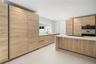 Kitchen featuring wood-finish cabinetry, a waterfall-edge island with countertop, recessed lighting, a built-in wall oven, and a single-basin sink wit