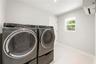 Laundry space featuring wall-mounted ductless climate control, recessed ceiling lighting, a window, and neutral-toned flooring