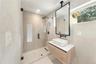 Cabana Bath Floating vanity with rectangular vessel sink and countertop, ceiling-mounted mirror with black frame, walk-in shower with frameless glass 