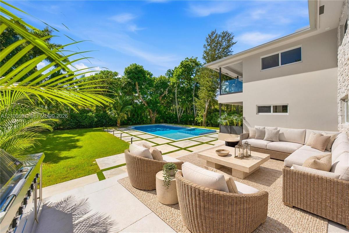 Virtually Staged: Outdoor living area featuring a paved patio, swimming pool with integrated spa, manicured lawn, and built-in stainless steel grill