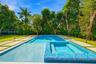 In-ground swimming pool with an integrated spa, mosaic tile finish, concrete paver decking, and mature landscaping
