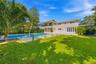 Exterior facade featuring natural stone veneer, in-ground swimming pool with integrated spa, manicured lawn, tiered patio, and second-story balcony wi