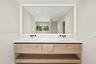 Floating wood-finish vanity with dual integrated sinks, white quartz countertop, matte black wall-mounted faucets, and large LED-backlit mirror