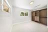 Custom built-in wood-finish wardrobe system with integrated shelving and drawers, neutral carpeting, and multiple dual-pane windows