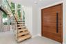 Entryway featuring a horizontal-plank wood door with a vertical matte black handle, a floating staircase with wood treads, and a glass panel railing