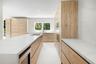 Kitchen featuring light wood-finish cabinetry, quartz countertops with full-height backsplash, a large center island, built-in stainless steel applian