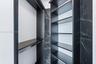 Built-in closet organization featuring matte black shelving, hanging rods, and dark stone-patterned wall surfacing