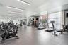 Fitness center featuring full-wall mirrors, recessed linear lighting, rubber flooring, and floor-to-ceiling windows with sheer drapery