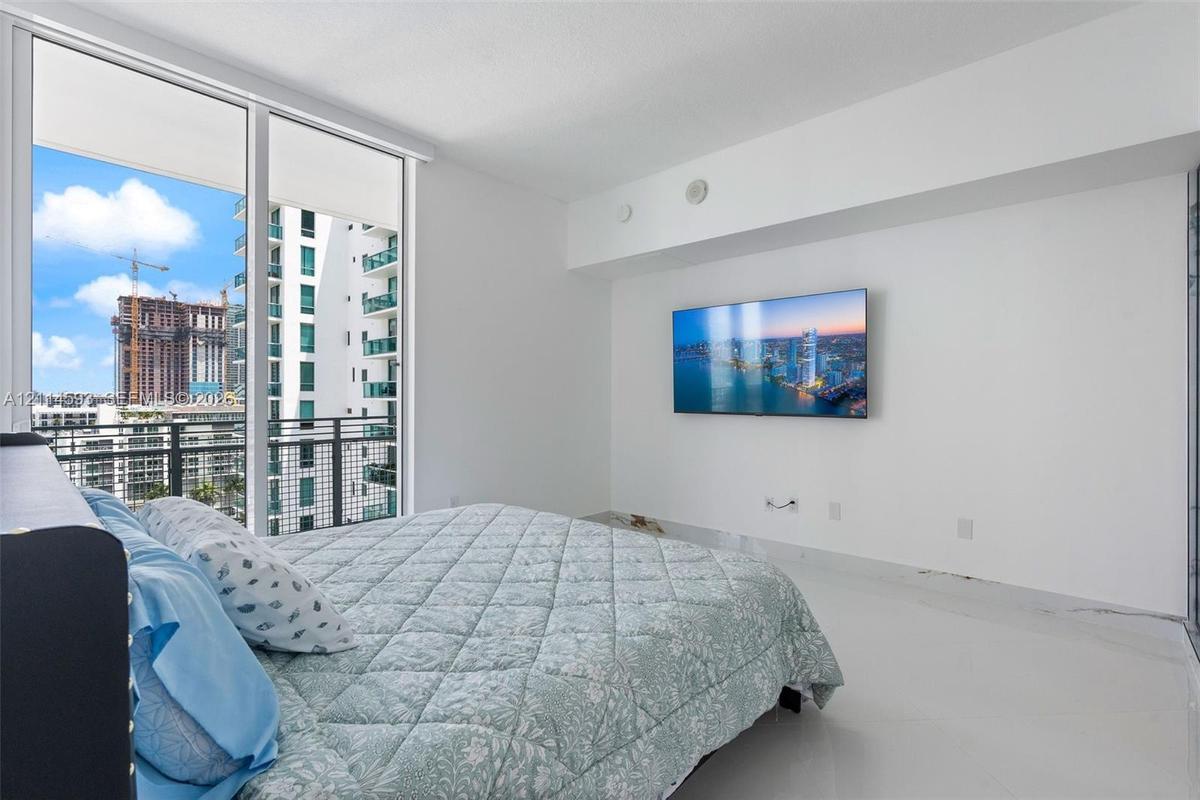 Floor-to-ceiling windows featuring access to a private balcony with metal railing and polished white flooring
