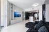 Living area featuring large-format veined stone wall cladding, built-in floor-to-ceiling cabinetry, polished tile flooring, and a kitchen island with 