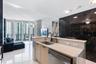 Kitchen featuring a light-toned cabinetry peninsula with stone-finish countertops, stainless steel sink with matte black faucet, and polished large-fo