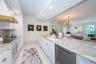 Custom Cucina with a Grand Peninsula, Quartzite Counter & Backsplash Accessorized Stainless Appliances.