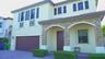 Two-story exterior featuring a stone-veneer facade, arched entryway, brick-paver driveway, decorative window shutters, and a multi-car garage