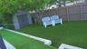Backyard featuring synthetic turf, tiered stone-block retaining walls, a grey storage shed, and a solid-panel privacy fence