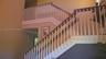 Staircase featuring a dual-toned wood handrail, vertical white balusters, and a high-ceiling configuration