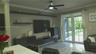 Living area featuring multi-panel glass French doors, wood-finish flooring, crown molding, built-in dark cabinetry with floating shelving, and a moder