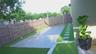 Fenced backyard featuring a concrete patio, synthetic turf lawn, and stone paver walkway