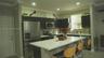 Kitchen featuring dark-finish cabinetry, a white countertop island, stainless steel appliances, a tile backsplash, and recessed lighting