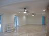 Polished stone flooring, crown molding, chair rail trim, dual ceiling fans with integrated lighting, and glass-paned French doors