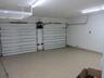 Two-car garage featuring dual overhead doors, overhead storage shelving, interior LED lighting, and speckled epoxy flooring