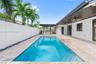 Outdoor space featuring a rectangular swimming pool, stone-tiled patio, built-in outdoor bar with a pergola, covered lanai with ceiling fans, and a so