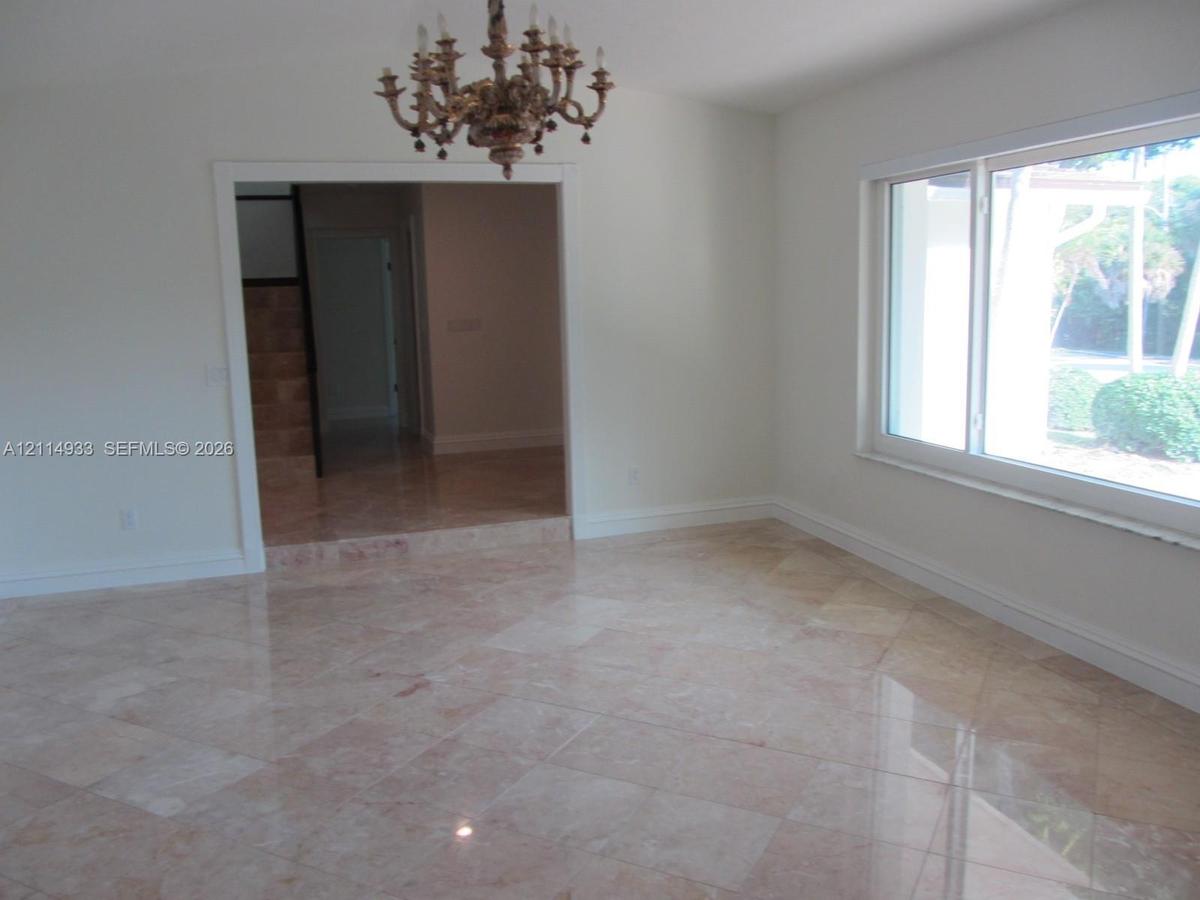 Polished stone tile flooring, ornate multi-arm chandelier, and expansive picture window