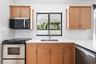 Kitchen featuring wood-finish cabinetry, solid surface countertops, a stainless steel undermount sink, matching stainless steel appliances, and a sing