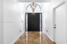Foyer featuring double entry doors with vertical glass sidelights, an arched transom window, a multi-tiered metal chandelier, and diagonal-set stone-f