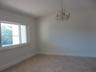 Vaulted ceiling, multi-light crystal chandelier, large-format tile flooring, and a wide horizontal window