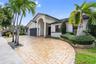 Stucco exterior featuring an arched entryway, a stone-paver driveway, and an attached multi-car garage