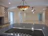 Kitchen featuring dark stone countertops, a glass-top cooktop, light wood cabinetry with built-in wine storage, recessed lighting, and a stained glass