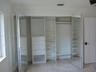 Custom reach-in closet featuring mirrored bi-fold doors, integrated shelving, multi-level hanging rods, and built-in drawer storage