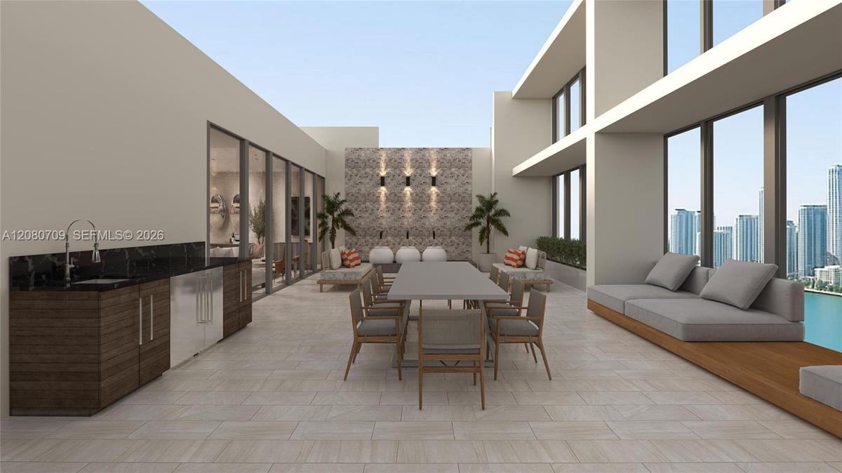 Expansive terrace featuring large-format tile flooring, a built-in outdoor kitchen with dark stone countertops, an integrated stone-clad wall accent, 
