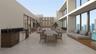 Expansive terrace featuring large-format tile flooring, a built-in outdoor kitchen with dark stone countertops, an integrated stone-clad wall accent, 