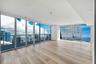 Open-concept interior featuring large-format tile flooring, stone-topped kitchen island, built-in cabinetry with integrated under-cabinet lighting, an