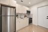 Kitchen featuring flat-panel cabinetry, quartz countertops, and stainless steel appliances including a refrigerator, built-in microwave, and electric 
