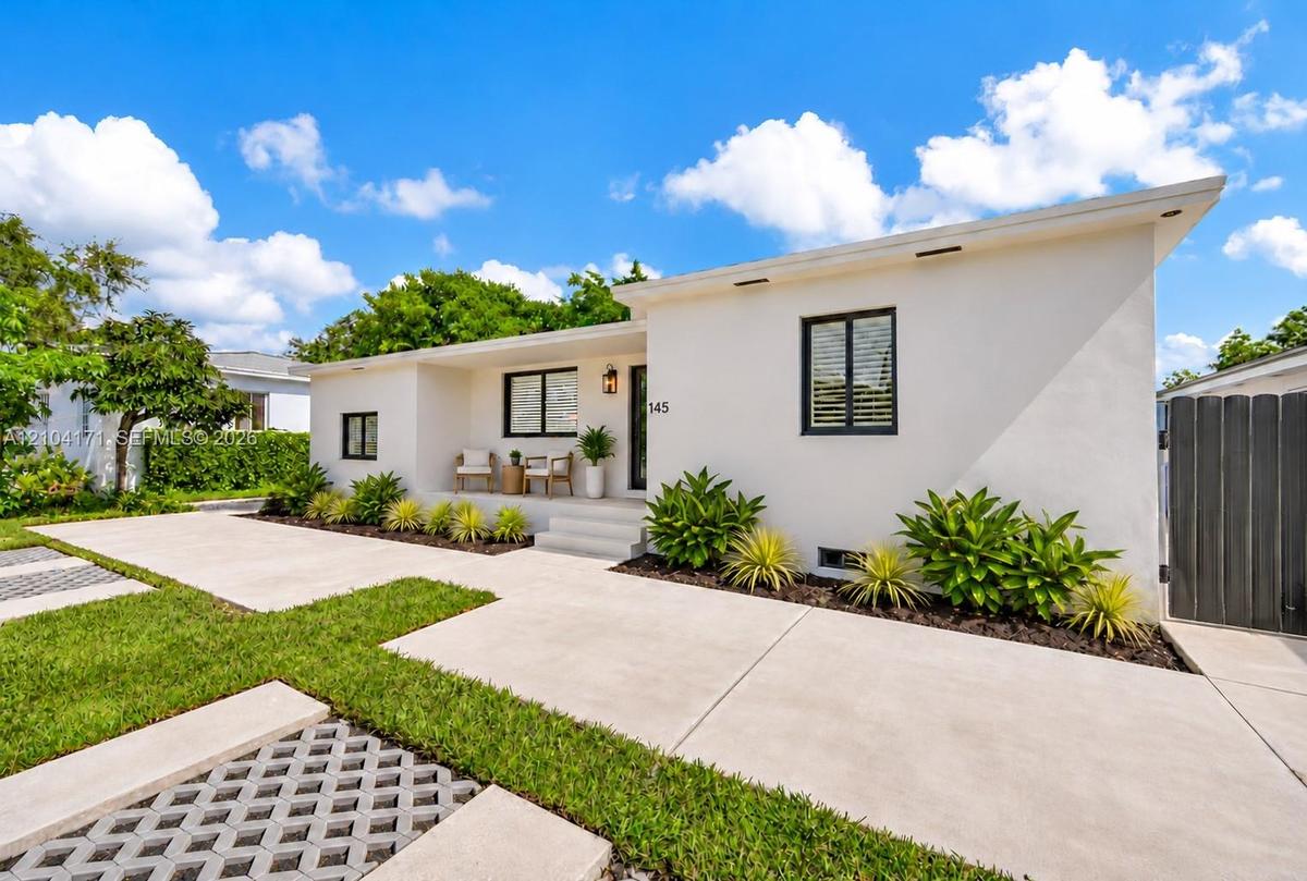 Single-story residence featuring a smooth stucco exterior, a concrete driveway, integrated recessed exterior lighting, black-framed windows, and a lan