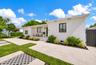 Single-story residence featuring a smooth stucco exterior, a concrete driveway, integrated recessed exterior lighting, black-framed windows, and a lan