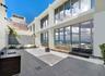 Expansive rooftop terrace featuring large-format tile flooring, floor-to-ceiling glass windows, a built-in outdoor kitchen with stone countertop, and 