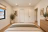 Neutral-toned interior featuring wood-finish flooring, recessed lighting, a single window with black framing, a bi-fold closet, and a multi-panel inte