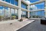 Expansive rooftop terrace featuring floor-to-ceiling glass wall panels, structured tile flooring, built-in wooden bench seating, and an integrated out