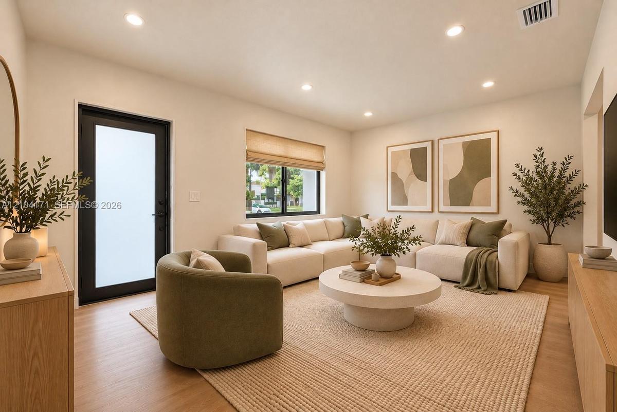 Neutral walls, wood-finish flooring, recessed lighting, and a black-framed exterior door with frosted glass