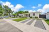 Exterior featuring a light-colored stucco finish, a level lawn, a detached storage structure, and fixed-pane windows