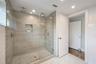 Walk-in shower featuring glass enclosure, ceiling-mounted rainfall showerhead, integrated tiled wall niche, and herringbone-patterned floor tile
