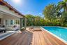 Rear exterior featuring a wood-finish deck, swimming pool, and wide-opening glass panel doors
