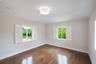 Neutral interior featuring wood-finish flooring, white plantation shutters, and a central drum flush-mount light fixture