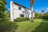 Stucco exterior featuring a clay tile roof, arched entryway, and manicured landscaping