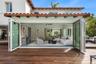 Stucco exterior featuring a clay tile roof, expansive wood decking, and multi-panel folding glass doors