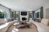 Living room featuring a stone-surround fireplace, multi-pane windows, recessed lighting, and wall-to-wall flooring