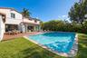 Stucco exterior with a clay tile roof, wood-finish decking, inground swimming pool, and folding glass wall systems
